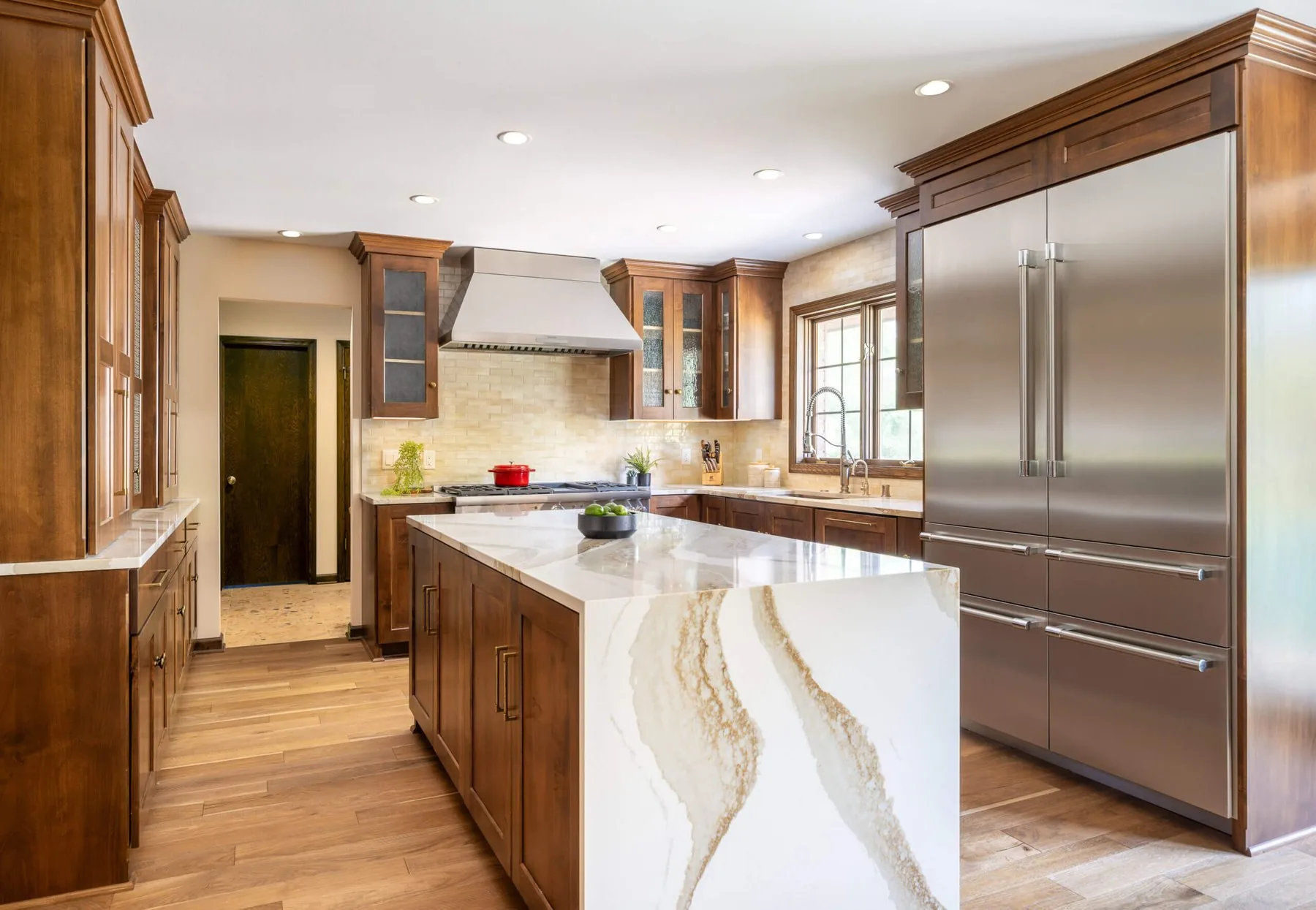 Kitchen with walnut cabinetry, a stone island, and a paneled range wall
