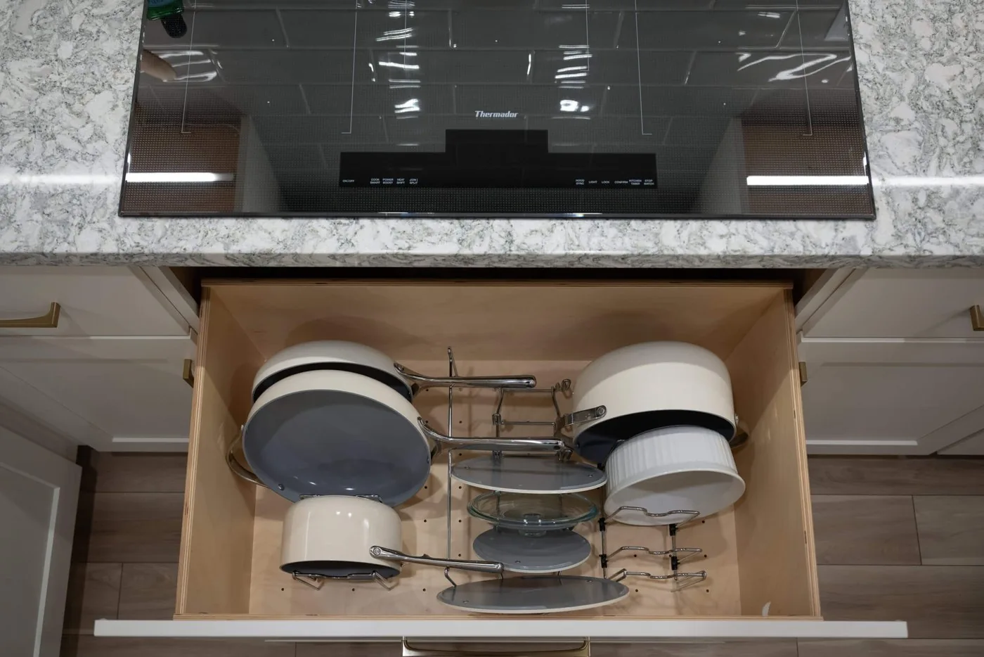 Deep kitchen drawer fitted with a rack that holds pot lids and cookware upright