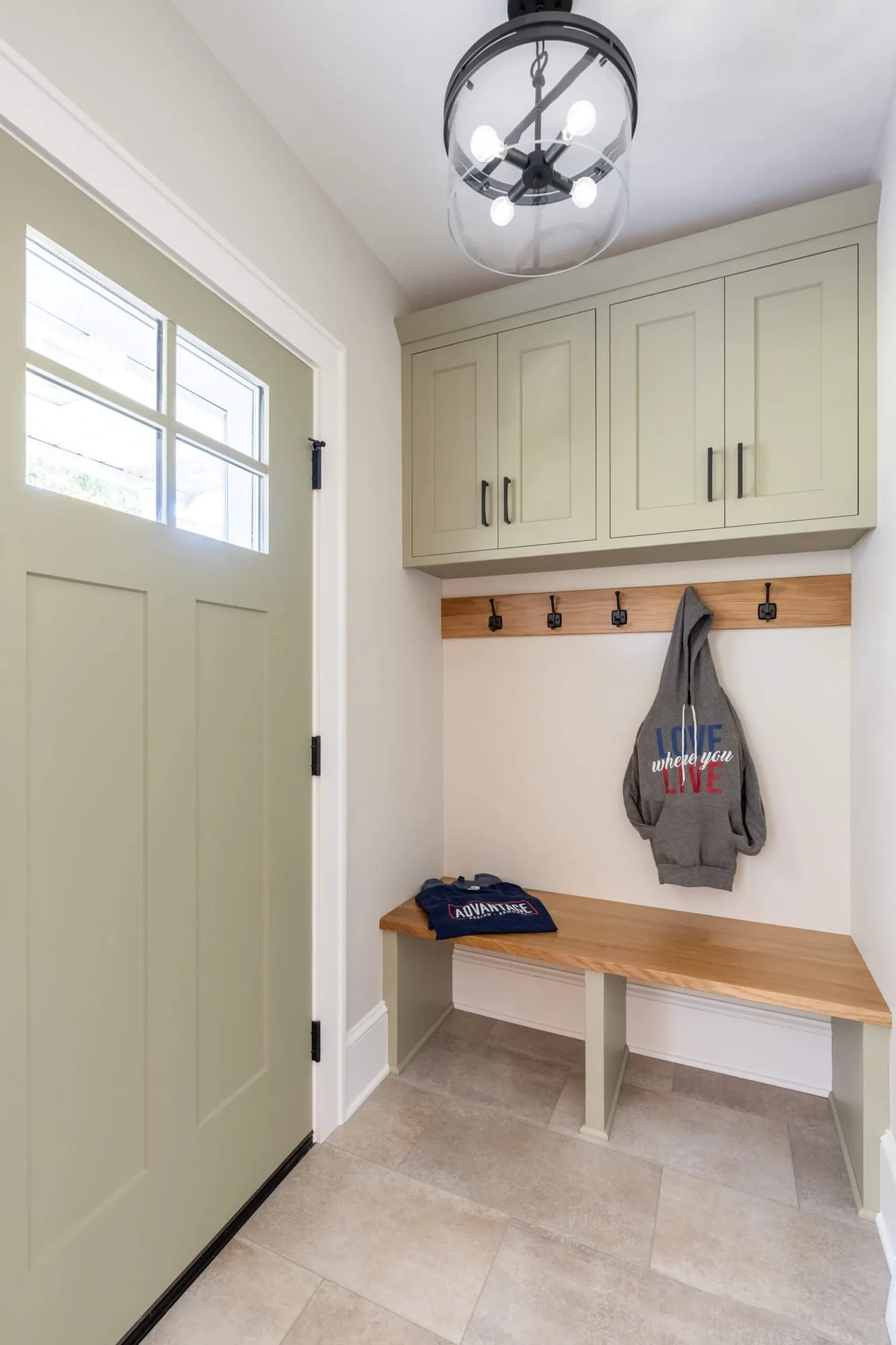 Mudroom with a built in bench, coat hooks, and painted upper cabinets
