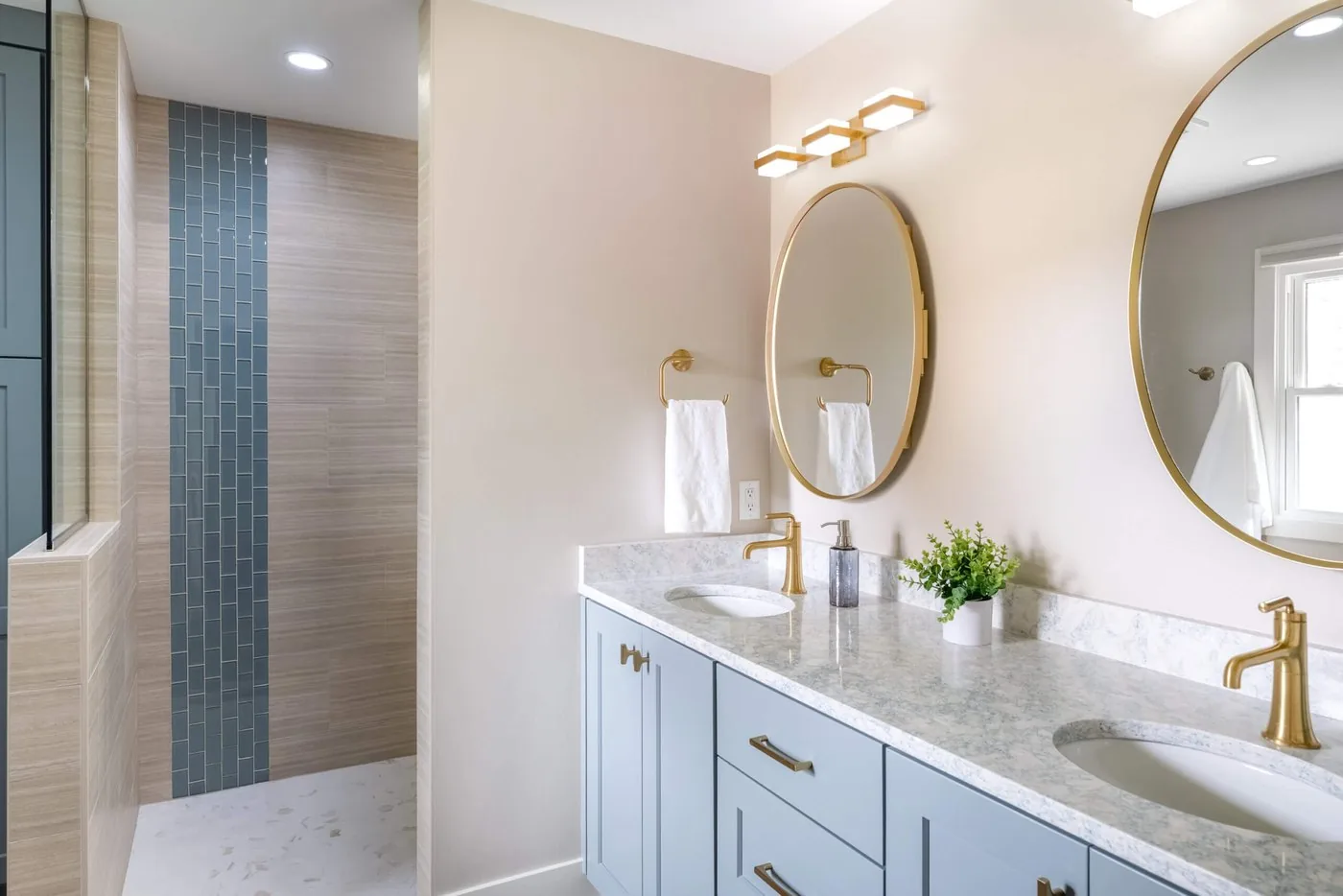 Bathroom with a double vanity, round mirrors, and a glass walk in shower