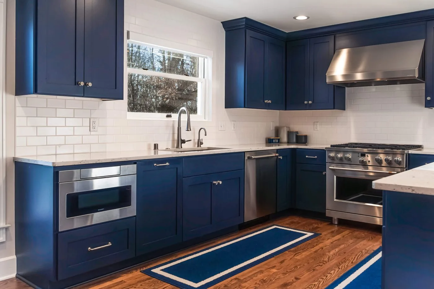 Navy shaker kitchen with stainless appliances and white subway tile