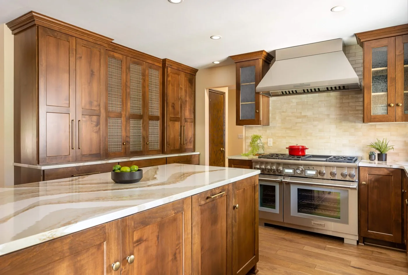 Kitchen with a stone waterfall island, glass front upper cabinets, and a professional range