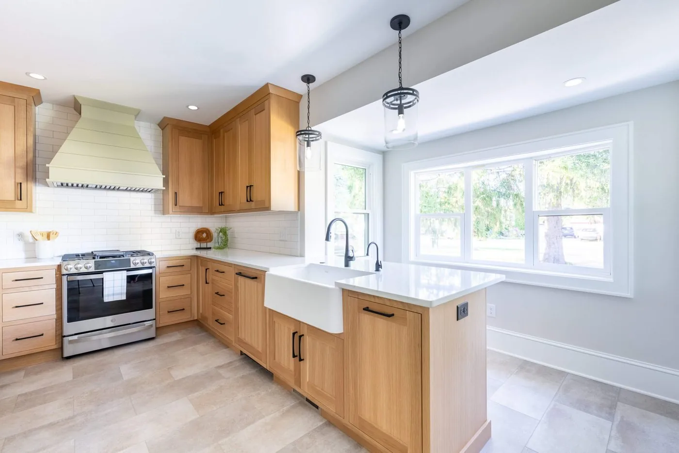 Kitchen with sage green and natural oak cabinetry, a farmhouse sink, and a stone island